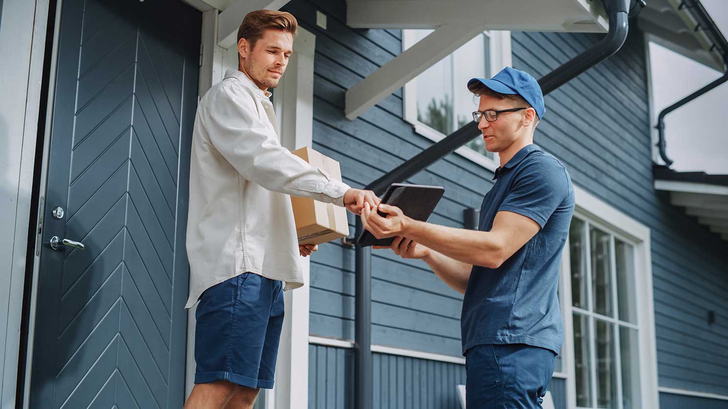 A courier collecting a signature on a tablet from a man he delivered a package to.