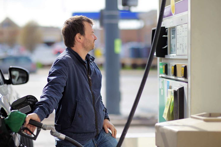 A delivery driver fills up his car with fuel